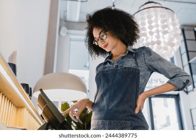 20s african beautiful waitress counting at cafe counter in restaurant, calculating funds and profit. Small business female owner selling food and beverages industry - Powered by Shutterstock