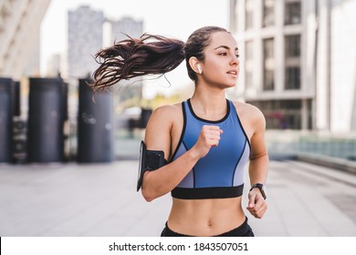 20s female jogger running listening to the music against urban landscape - Powered by Shutterstock