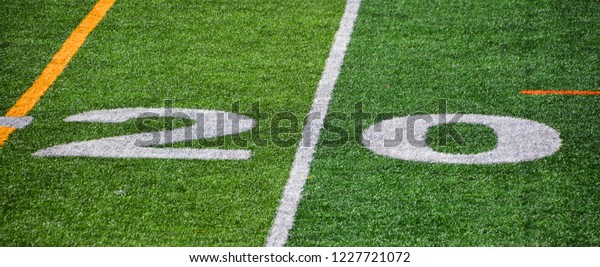 The 20-yard-line of an american football field with\
artificial turf