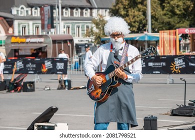 21 August 2021, Ufa, Russia: A metalhead street musician in costume of Colonel Sanders KFC performs rock music for the public