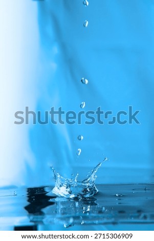 210.Water droplets fall vertically forming crown splash on impact. Blue gradient background enhances clarity, fluid motion, and surface tension in high-speed capture.