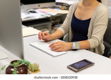 21/11/2020: Lady Works At Home With Computer While Wearing Electronic Tracker Wristband By Hong Kong Government To Monitor Those Under Compulsory Home Quarantines To Curb Spread Of Covid-19