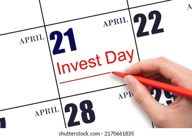 21st day of April.  Hand drawing red line and writing the text Invest Day on calendar date April 21.  Business and financial concept. Spring month, day of the year concept.