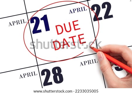 21st day of April. Hand writing text DUE DATE on calendar date April 21 and circling it. Payment due date. Business concept. Spring month, day of the year concept.