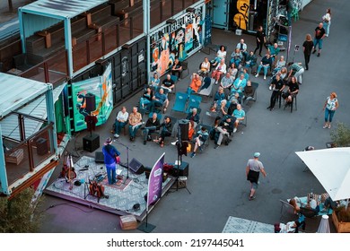 22 July 2022, Dusseldorf, Germany: People Sitting And Resting While Watching Musician Performing At Street Openair Festival