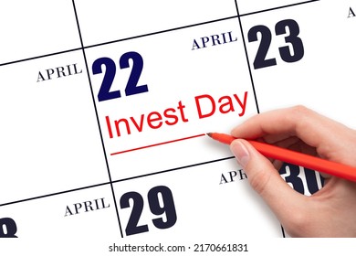 22nd day of April.  Hand drawing red line and writing the text Invest Day on calendar date April 22.  Business and financial concept. Spring month, day of the year concept.