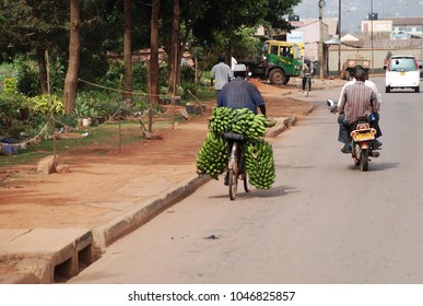 22nd of March 2012 - Scene from African street with a man on a bicycle with an overload of green bananas and two persons on a motor bike, Kampala, Uganda, Africa