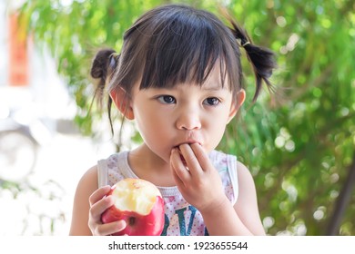 Portrait​ Image​ Of​ 2-3 Yeas​ Old​ Of​ Baby.​ Happy​ Asian Child Girl Eating And Biting An Red Apple. Enjoy Eating Moment. Healthy Food And Kid Concept.​ Sucking Fingers In The Mouth.