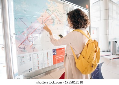 23 February 2021, Dubai, UAE: Woman in a medical mask during covid19 pandemia reading map to find a route in dubai metro