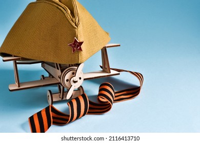 23 February, 9 May background - George ribbon, military cap and wooden plane on blue background. Copy space for text. Greeting card for holiday
