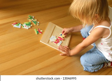 2-3 years old girl kneeling on the floor and solving jigsaw puzzle