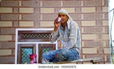 24 February 2021-Khatoo, Jaipur, India. Man with tea. Professional painter redo a living room, have a rest with a cup of tea. Adult sitting on ladder among paint tools and accessories during the break