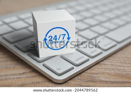 24 hours service icon on white block cube with modern computer keyboard on wooden table, Business full time service online concept