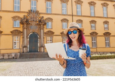 24 July 2022, Osnabruck, Germany: Student Girl With Laptop And Drinking Coffee, Going To The Entrance To The Campus Or Faculty Of Old University. Education In Europe Concept