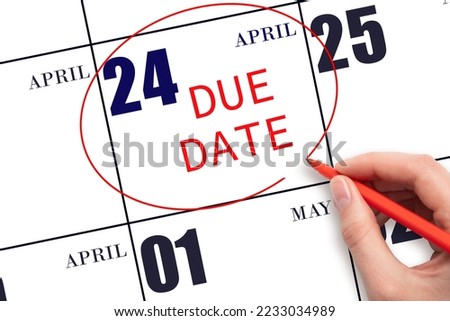 24th day of April. Hand writing text DUE DATE on calendar date April 24 and circling it. Payment due date. Business concept. Spring month, day of the year concept.