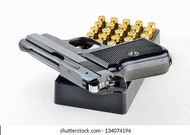 .25 caliber automatic handgun and box of ammunition against neutral background.