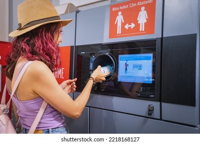 25 July 2022, Munster, Germany: A Student Girl Hands Over A Plastic Beverage Bottle For Recycling To Automated Machine. Eco Friendly Lifestyle And Cashback