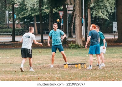 25 July 2022, Munster, Germany: Friends Playing Spike Ball Mini Beach Volleyball On A Green Grass Lawn. Leisure Sports And Fun Recreation With Friends