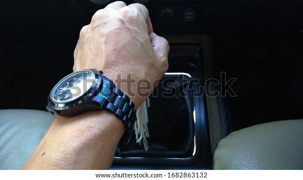 25 March\
2020, Bangkok - Thailand, left hand wearing a watch Handle the gear\
lever, the car\'s motion control\
system.
