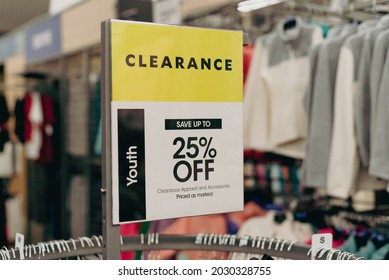 25 percent off discount sign with blurred woman clothing in background at fashion store in Texas, America. Product on sale display on top of round clothing rack.