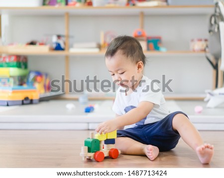 2.5 years baby boy.Little child boy playing stack with colorful wooden toys block alone.Kids play with educational toys at home.Day care and Kindergarten school.child development concept.