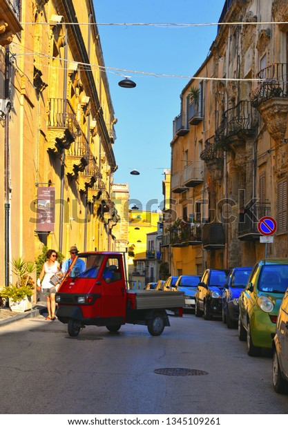 25.08.2018. View of a narrow street with\
red vintage Ape Piaggio car, old buildings and facades in the\
historical city of Agrigento in Sicily,\
Italy