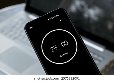 25-minute timer on phone to study with pomodoro method on laptop keyboard computer. Wide shot of office studying homework learning business environment.