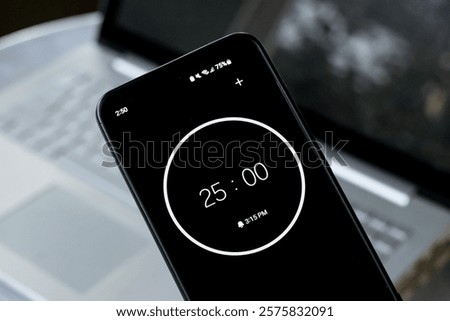 25-minute timer on phone to study with pomodoro method on laptop keyboard computer. Wide shot of office studying homework learning business environment.