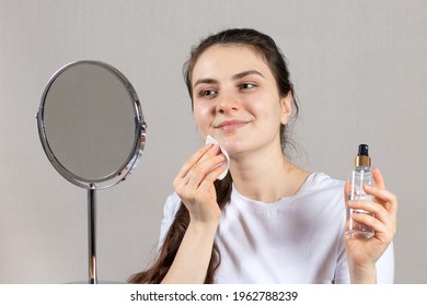 A 25-year-old Woman Holds A Face And Neck Tonic And A Cotton Pad. Anti-wrinkle Skin Care, Vitamins And Acids For The Face