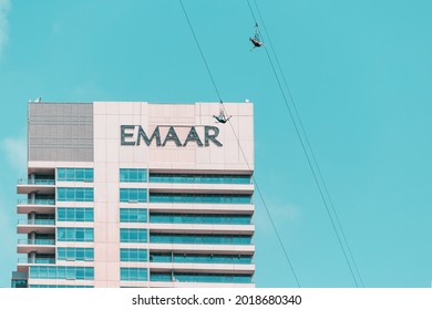 26 February 2021, UAE, Dubai: Two Adventurers Fly Down A Zip Line Rope In An Extreme Flight In Dubai Marina Against Emaar Logo