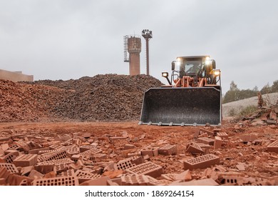 27.10.2020. Riga, Latvia: 
Hitachi Heavy Machinery Wheel Loader At A Construction Site Picking Up Sand And Piles Of Red And Black Bricks.