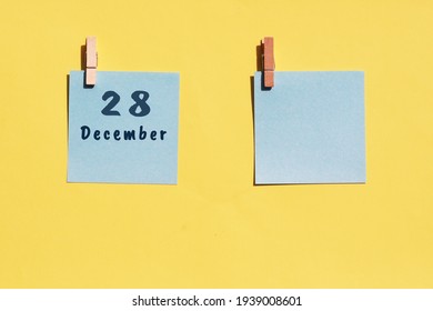 28 December. 28th day of the month, calendar date. Two blue sheets for writing on a yellow background. Top view, copy space. Winter month, day of the year concept.