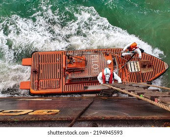 28August2022 At Yangtze River, China. A Sea Pilot Is Climbing On A Ladder While A Pilot Boat Is Alongside A Cargo Ship. A Pilot Wear PPE Suit During Embarking Due To COVID-19 Situation In China.