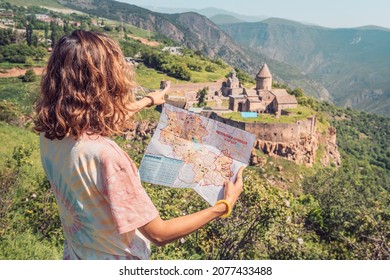 29 May 2021, Tatev, Armenia: woman looks at the nearest sights on the map with the Armenian ancient monastery of Tatev in the background