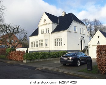 29th of January 2020 - Scene from Danish suburban street with parked Tesla car  in the driveway in front of a beautiful white mansion, Aalborg, Denmark