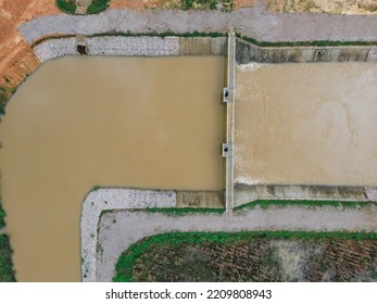 2D Aerial View Weir Or Water Dam Is Made Of Cement. Helps To Slow Down The Large Amount Of Water From The Top To The Bottom, Around The Green Trees.