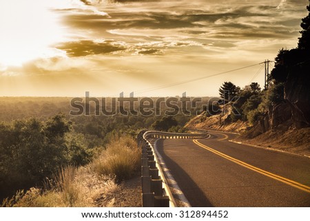 2-lane road during sunrise or sunset with view of valley in the background with a high dynamic sky