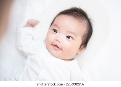 A 2-month-old baby who is stared at by his dad and looks back with a smile - Shutterstock ID 2236082909