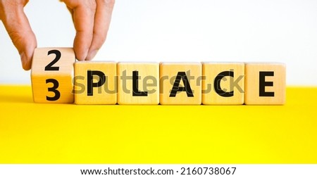 From 3 to 2 place symbol. Businessman turns wooden cubes and changes concept words 3 place to 2 place. Beautiful yellow table white background. Business and from 3 to 2 place concept. Copy space.