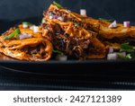 3 Beef Birria Tacos Stacked on Black Plate