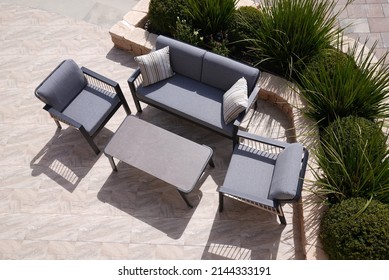 3 black and beige sofas and a table made of metal in the courtyard and garden on the garden floor, comfortable sofa, shot from above
