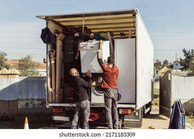 3 Colleagues Of A Moving Company Load A Dishwasher Onto The Truck