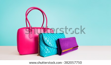 3 colorful fashion bags purses isolated on light blue background. 