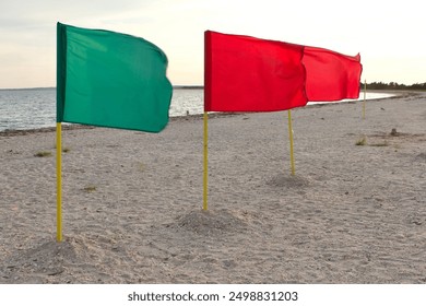 3 flags rippling and blowing in the wind on an abandoned sandy beach by the bay near the long island sound on an overcast day - Powered by Shutterstock