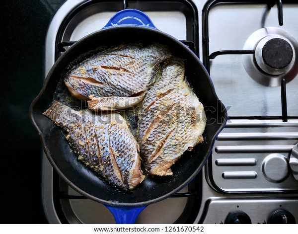 3\
fried pickled fish fillets in a blue pan on a gas stove background\
topical food of the people in Isaan.  Food in\
Thailand