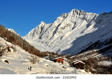 3 log cabins in an otherwise empty valley in the swiss alps. In the distance a glacier leading to the famous Aletsch glacier