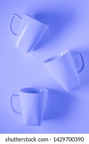 3 Monochromatic Blue Coffee Mugs Scattered On Blue Background With Blank Empty Room Space For Text, Copy, Or Copyspace. Modern Top View Concept Of Three Several Cups With Solid Background Backdrop