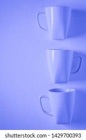 3 Monochromatic Blue Coffee Mugs Lined Up In A Row On Blue Background With Blank Empty Room Space For Text, Copy, Or Copyspace. Modern Top View Concept Of Three Cups With Solid Background Backdrop