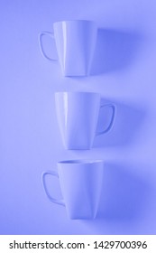 3 Monochromatic Blue Coffee Mugs Lined Up In A Row On Blue Background With Blank Empty Room Space For Text, Copy, Or Copyspace. Modern Top View Concept Of Three Cups With Solid Background Backdrop