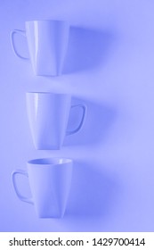 3 Monochromatic Blue Coffee Mugs Lined Up In A Row On Blue Background With Blank Empty Room Space For Text, Copy, Or Copyspace. Modern Top View Concept Of Three Cups With Solid Background Backdrop